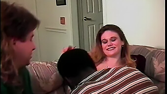 A Young Brunette Girl Gives A Blowjob To A Man While Another Black Man Has Sex With Her In A Rough Manner.